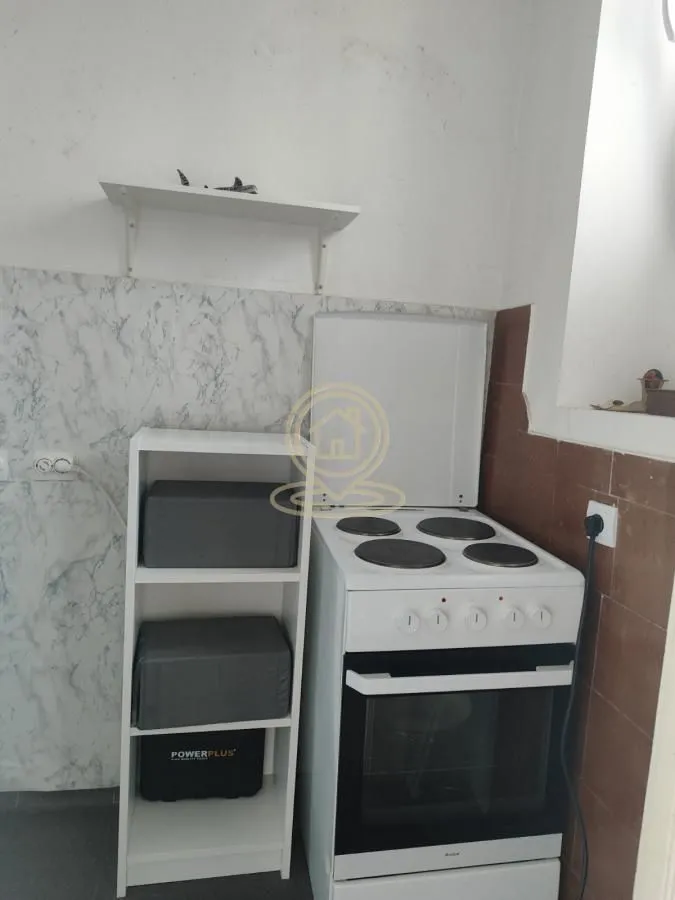 Small kitchen with a white electric stove and a wall shelf.