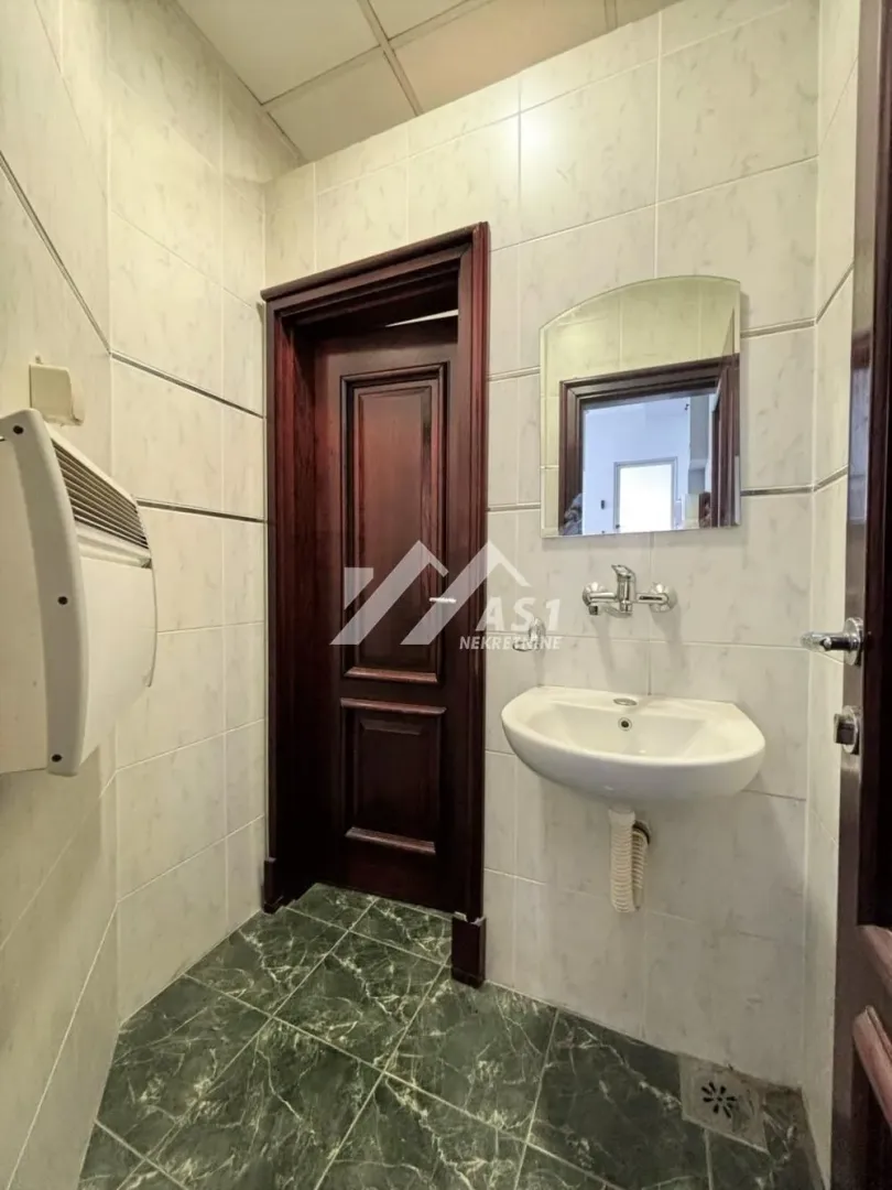 Smaller bathroom lined with ceramic tiles featuring a sink and a mirror.