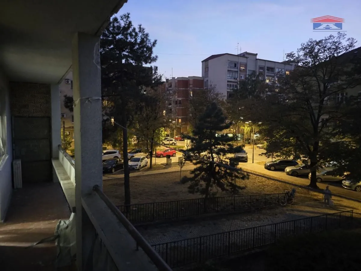 Pogled sa balkona na dvorište i okolne zgrade u sumrak.