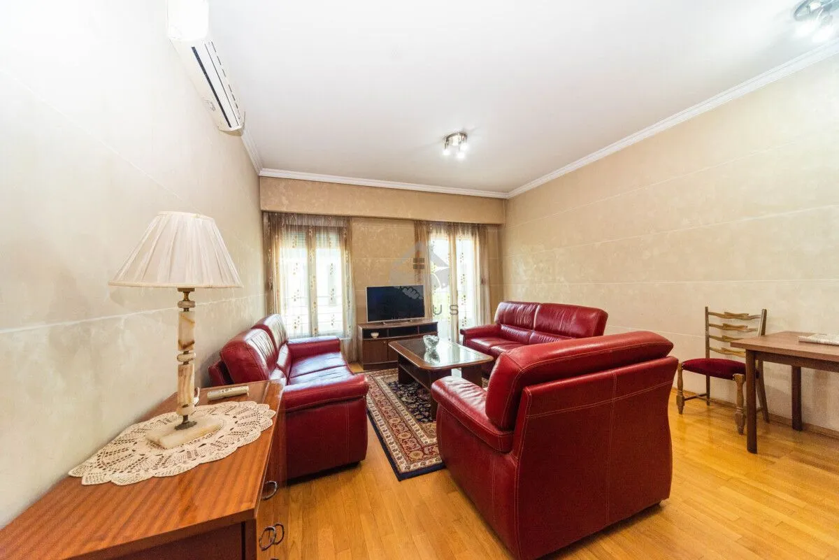 Living room with red leather sofas, TV, and a dining table.