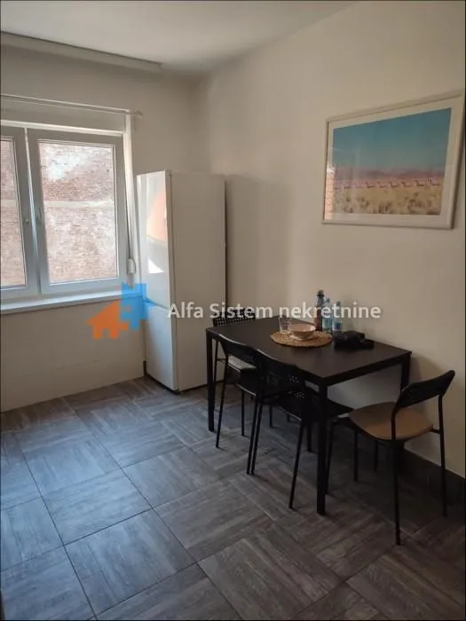 Manja kuhinja sa trpezarijskim stolom i frižiderom.