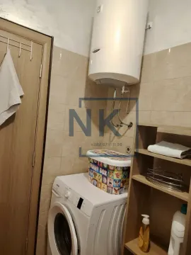 Bathroom with a washing machine, water heater, and a wooden shelf. - image 9