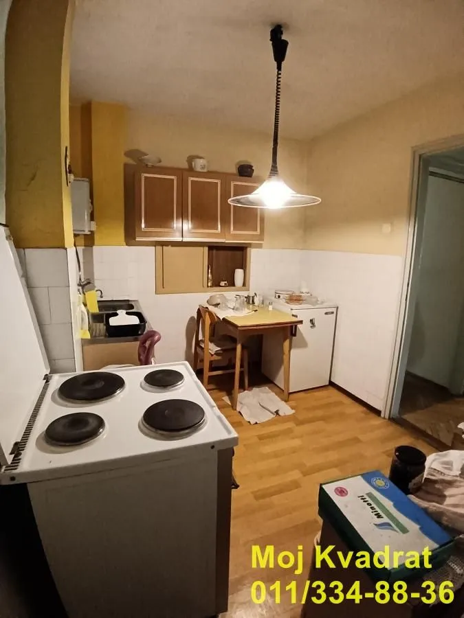 Starija kuhinja sa trpezarijskim stolom i šporetom.