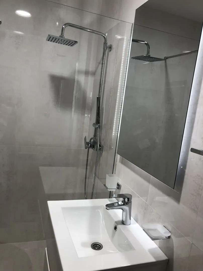 Modern bathroom with a shower cabin and a white sink.