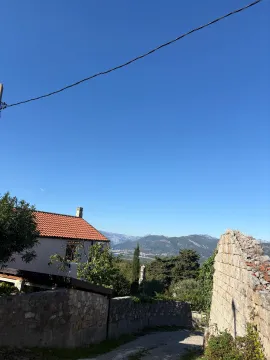 Eksterijer kuće sa kamenim zidom i pogledom na planine. - image 8