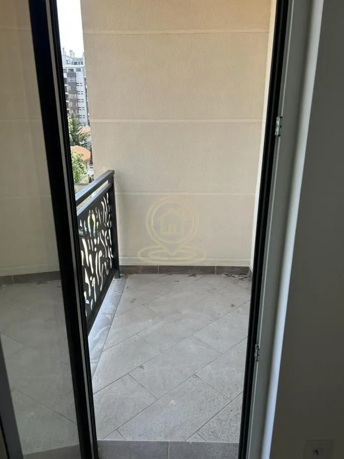 Pogled na popločanu terasu sa metalnom ogradom kroz otvorena balkonska vrata.