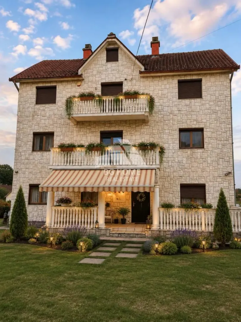 Front view of a three-story house with a stone facade, balconies, and a landscaped yard.