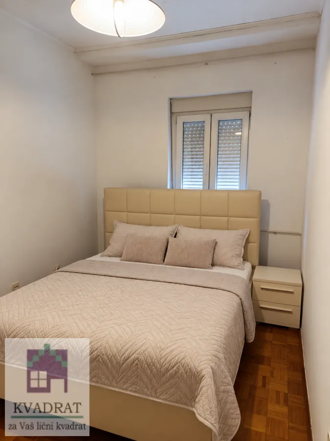 Spavaća soba sa bračnim krevetom i noćnim ormarićem.