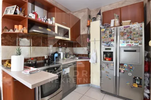 Kuhinja opremljena drvenim elementima, kućnim aparatima i velikim frižiderom. - image 3