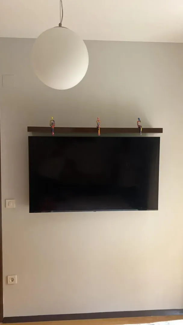 Detalj sa zidom, televizorom i ukrasnom policom.
