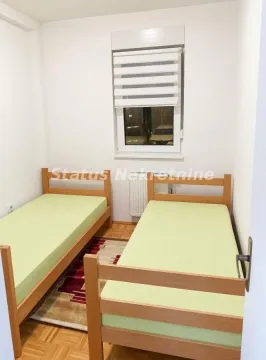 Manja spavaća soba sa dva drvena kreveta i prozorom. - image 7
