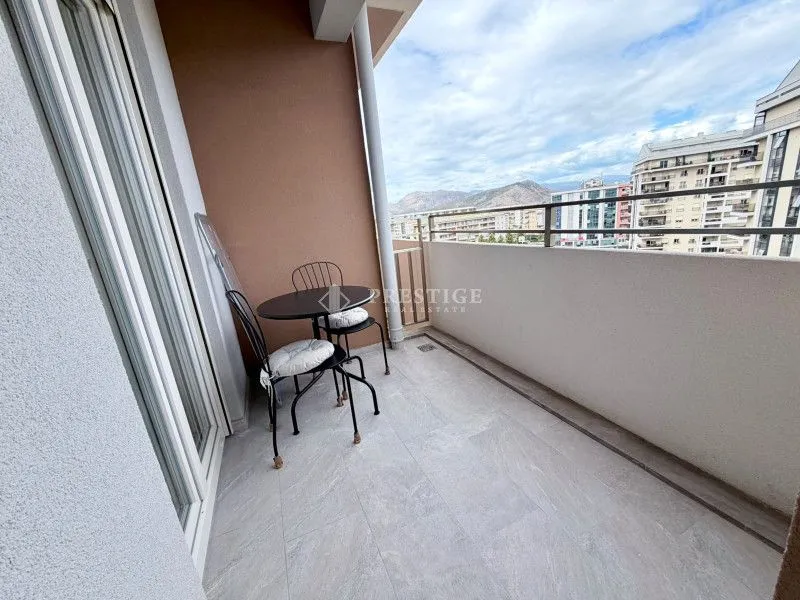 Manji namješten balkon sa stolom i dvije stolice i pogledom na grad.