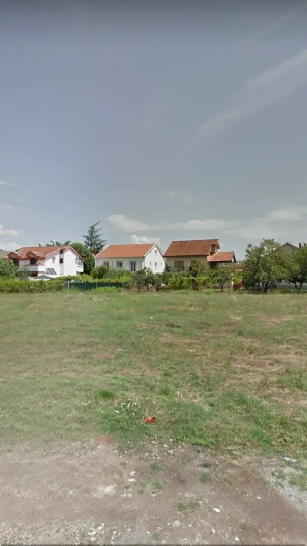 Pogled na prostrani plac sa kućama u pozadini.