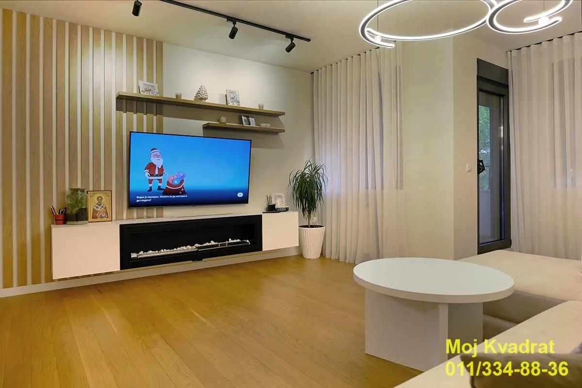 Modernly furnished living room with a TV and decorative lighting.
