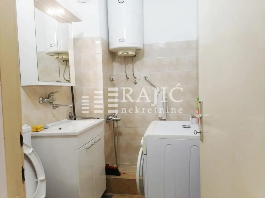 Small bathroom with sink, toilet, water heater and washing machine.