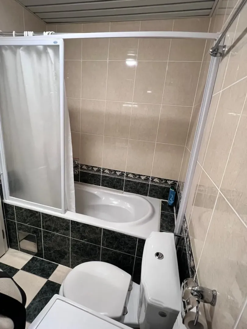 Kupatilo sa kadom, toaletom i keramičkim pločicama.