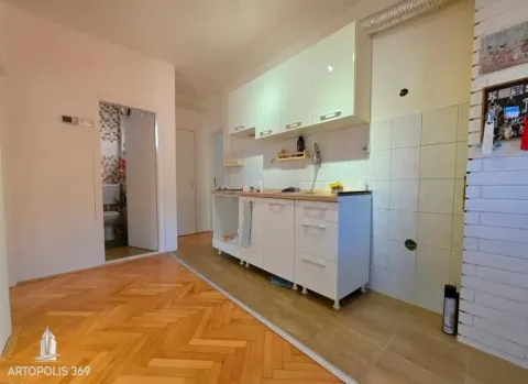 Kuhinja sa belim elementima i pogledom na kupatilo u pozadini. - image 6