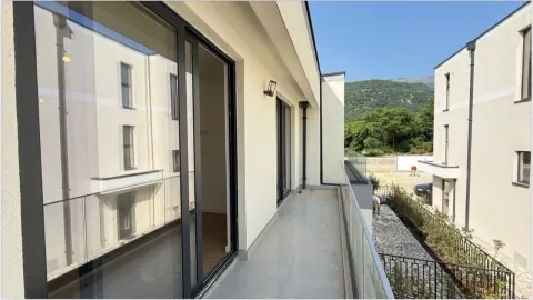 Spacious balcony with glass railing and a view of surrounding buildings and nature. - image 5