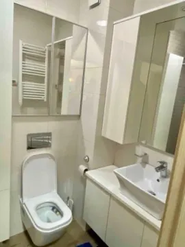Modernly equipped bathroom with white cabinets and a mirror. - image 11