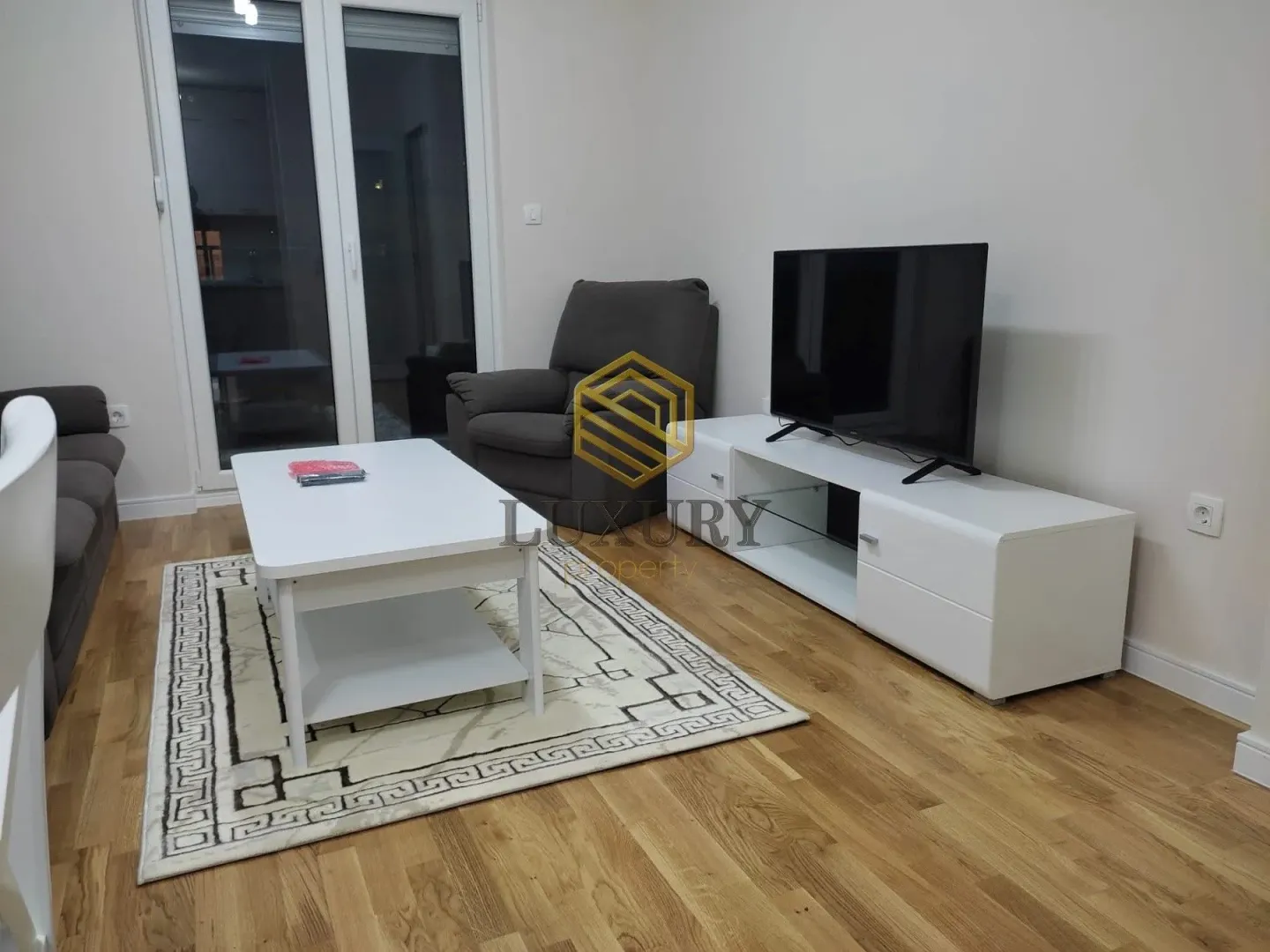 Dnevna soba sa garniturom, stočićem i televizorom.