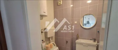 Manje kupatilo sa lavaboom, ogledalom i toaletom obloženo pločicama. - image 3