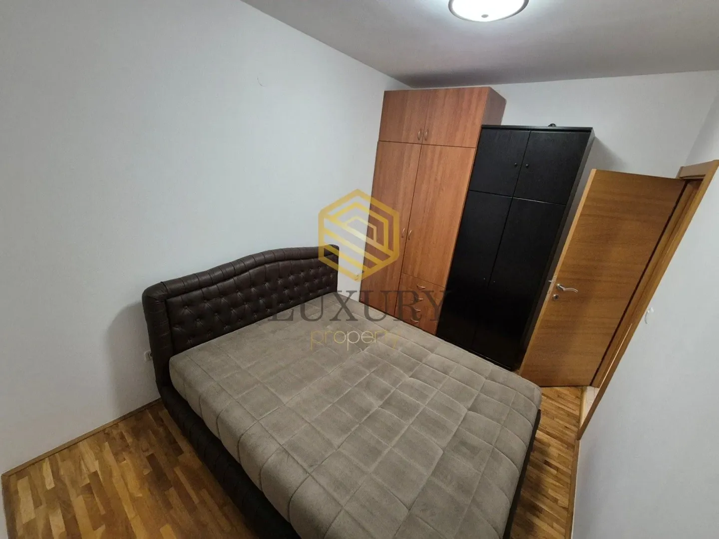 Bedroom with a double bed, wardrobes, and wooden flooring.