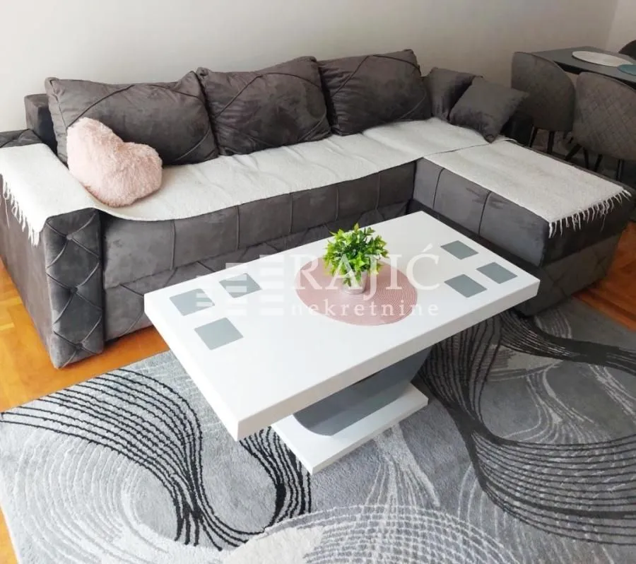 Living room with a sectional sofa, coffee table and rug.