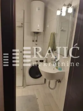 Small bathroom with a shower cabin, sink, washing machine, and water heater. - image 10