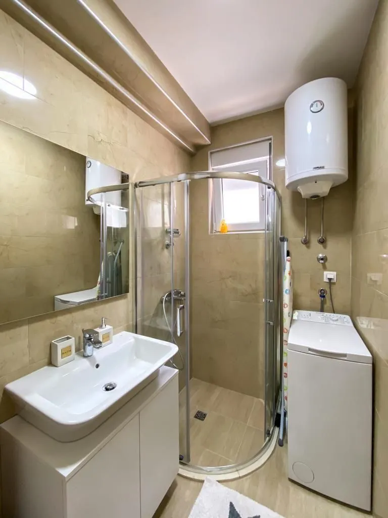 Bathroom equipped with a washbasin, shower cabin, and washing machine.