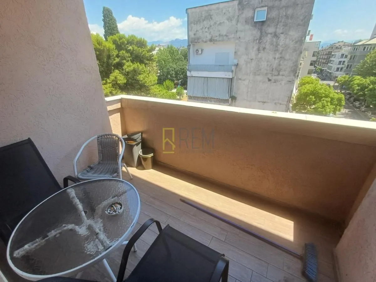 Manji namješteni balkon sa stolom, stolicama i pogledom na okolne zgrade.