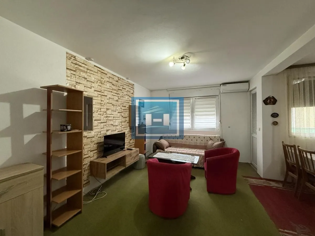 Dnevna soba sa garniturom, foteljama i televizorom.