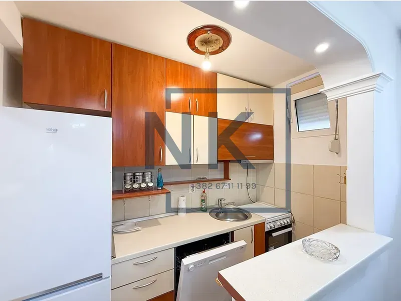 Manja opremljena kuhinja sa drvenim elementima i šankom.