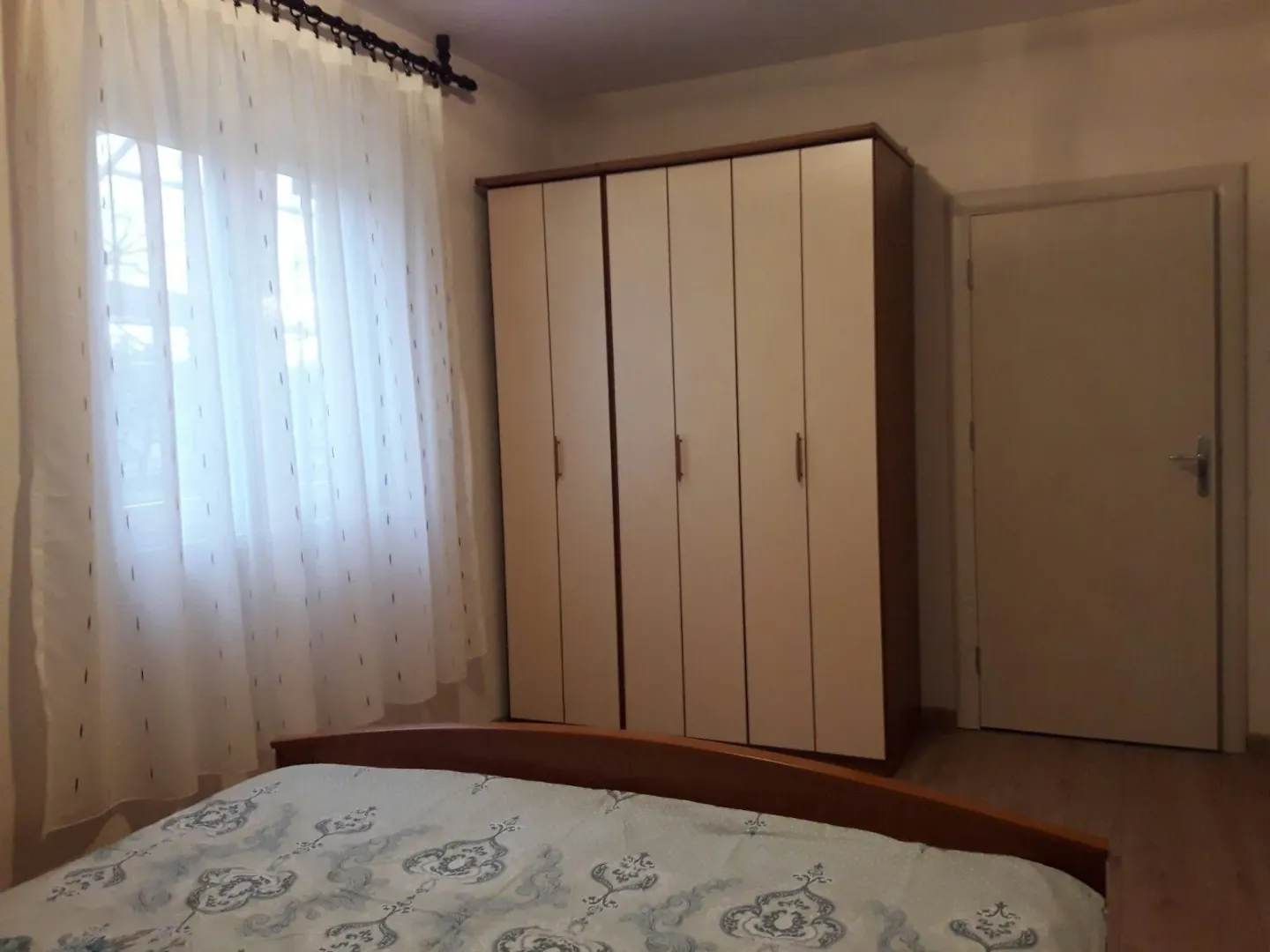 Simply furnished bedroom with a wardrobe and bed.