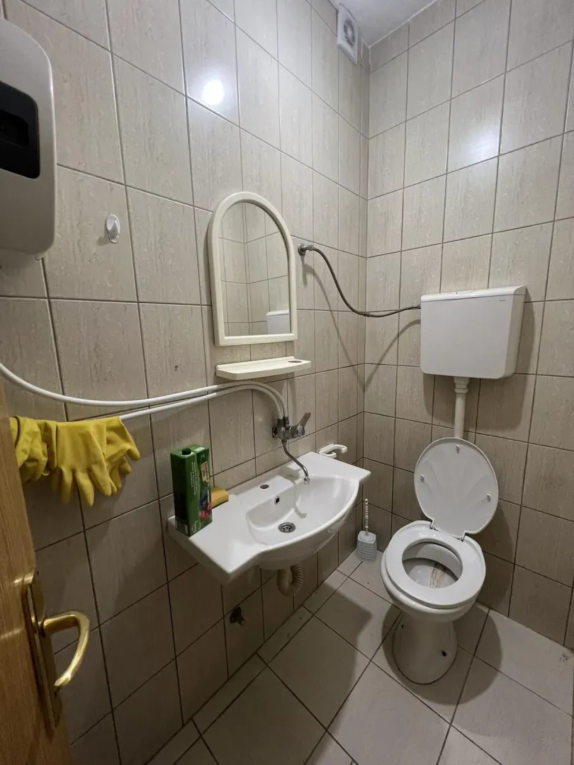 A small bathroom with a toilet, sink, and mirror.
