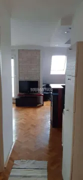 View from the hallway into the living room with parquet flooring and a television. - image 3