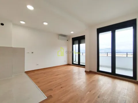 Prazna dnevna soba sa drvenim podom i izlazom na terasu. - image 3