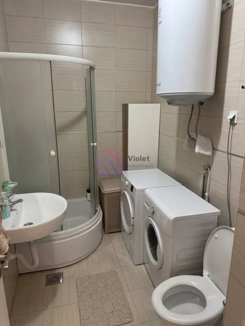 Bathroom equipped with a shower cabin, washbasin, toilet, water heater, and washing machine.