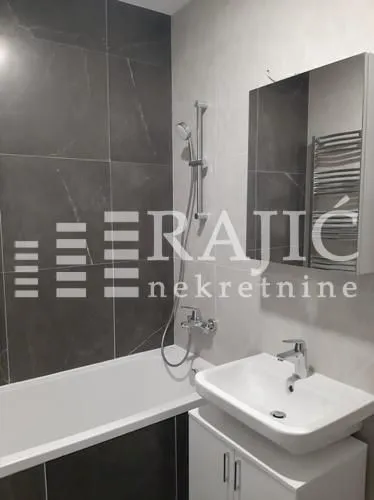 Modernly equipped bathroom with a bathtub, washbasin, and mirror.