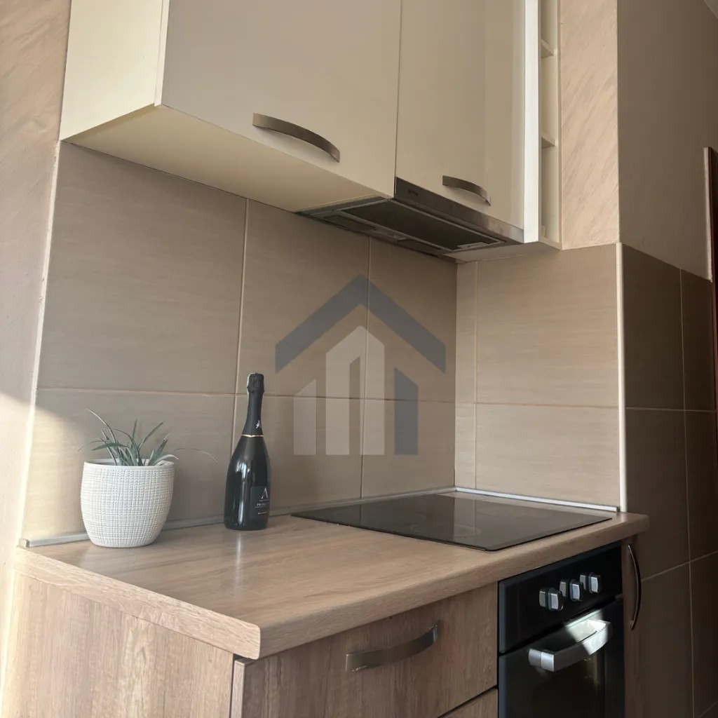 Small kitchen with a built-in cooktop, oven, and beige cabinetry.