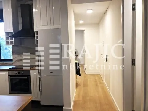 View of the kitchen with white cabinetry and a hallway in the apartment.