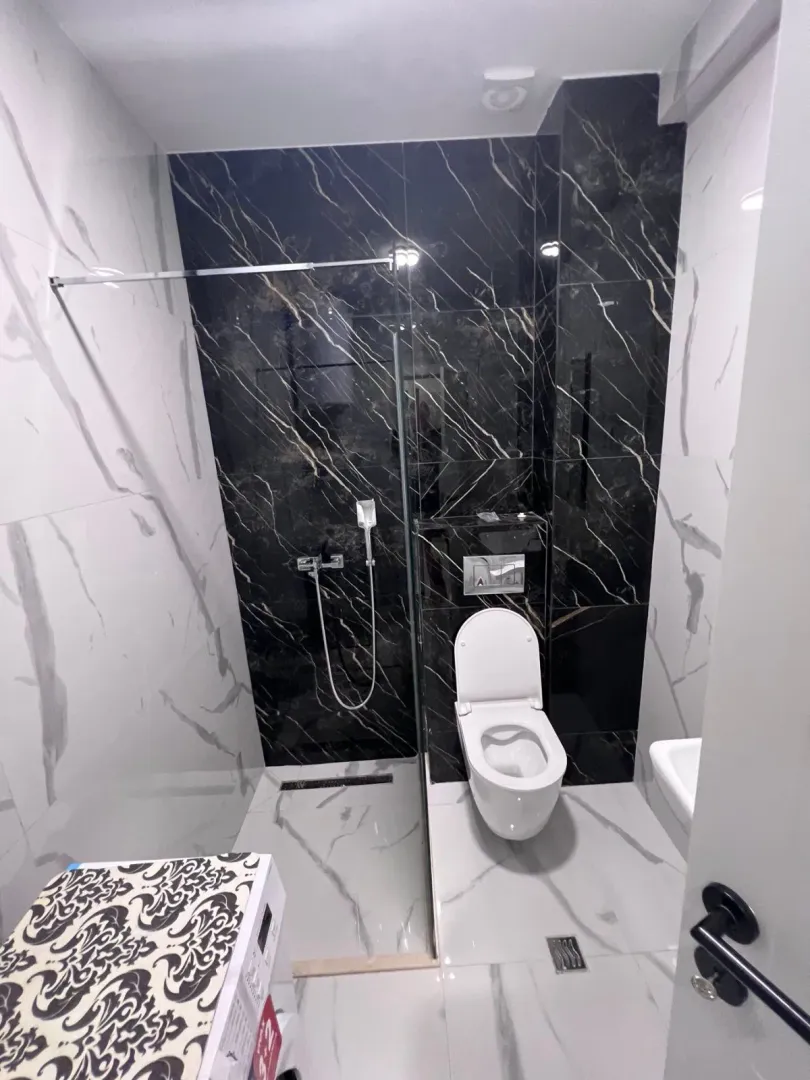 Moderne kupatilo sa tuš kabinom i crnim mermernim pločicama.