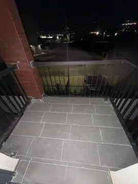 Popločani balkon sa crnom ogradom i pogledom na noćni grad. - image 8
