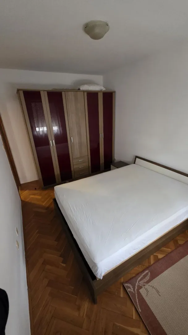 A bright bedroom with a double bed and a large wardrobe.