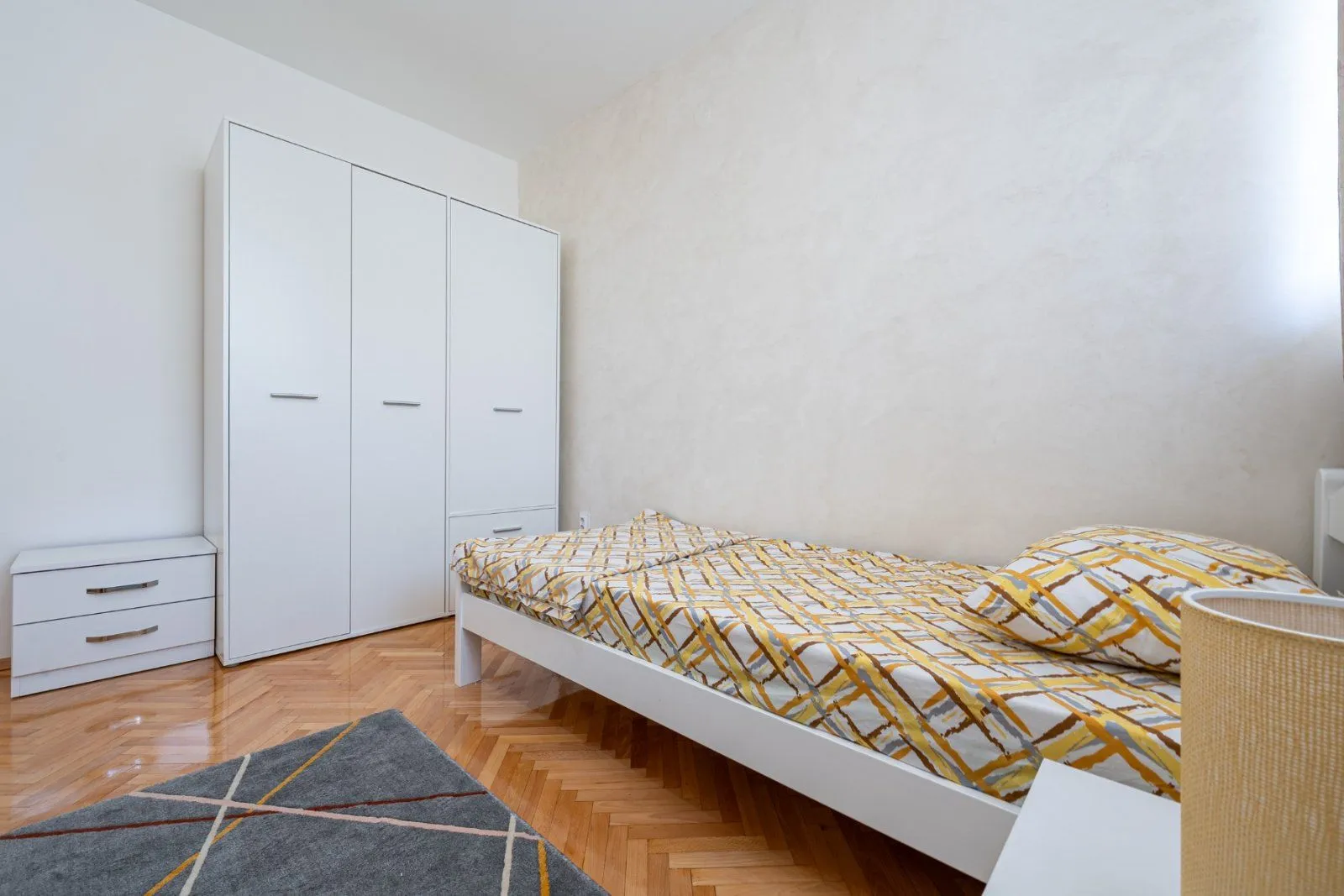 Furnished bedroom with a bed and a white wardrobe.