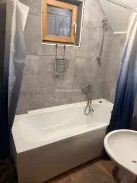 Bathroom with a bathtub, grey tiles, and a window. - image 6