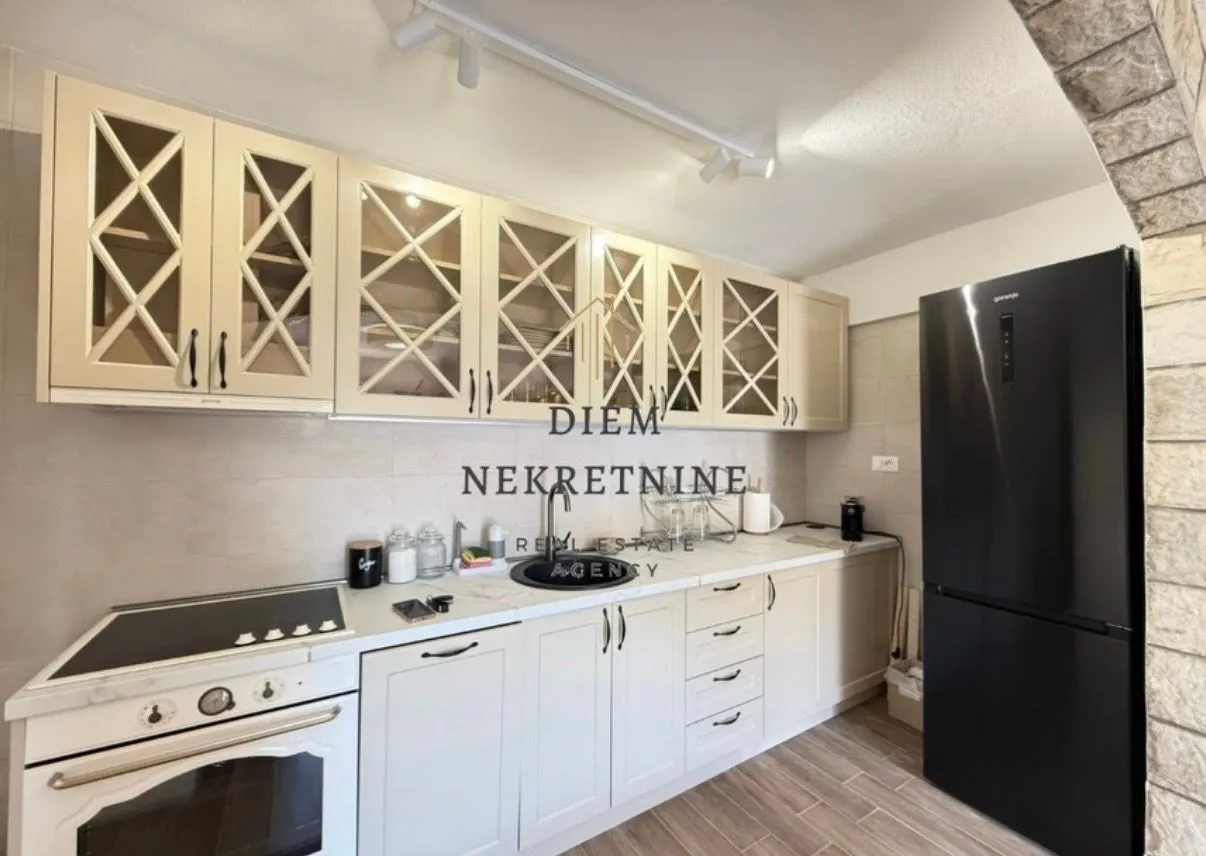 Modern kitchen with light cabinetry and a black refrigerator.