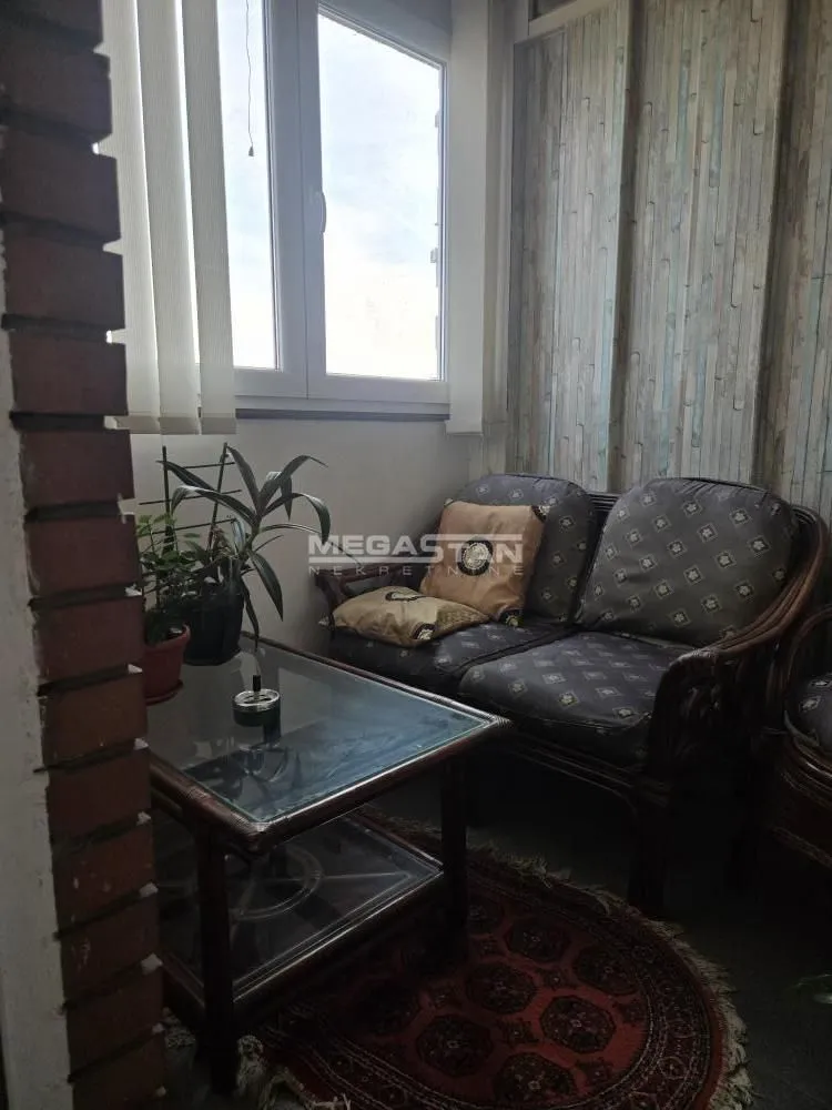 Zastakljena terasa sa garniturom za sedenje i stočićem.
