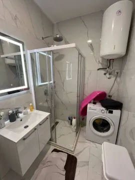 Savremeno opremljeno kupatilo sa tuš kabinom, umivaonikom i veš mašinom. - image 4