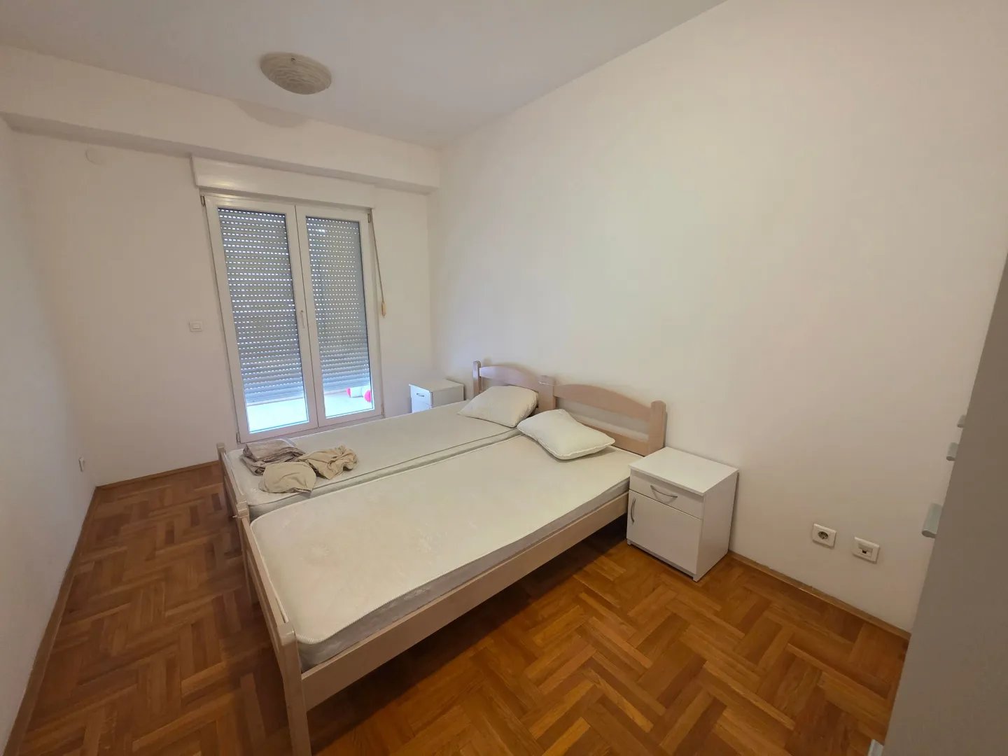 Bedroom with a double bed, bedside tables, and parquet flooring.