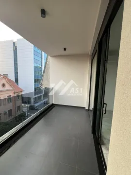 Covered balcony with dark tiles and a glass railing. - image 9